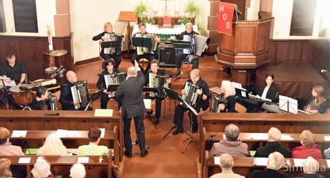 Manfred Klepper dirigierte neun Harmonika-Spieler, zwei Keyboarderinnen und einen Trommler beim Konzert in der evangelischen Kirche.Foto: Michael Sittig